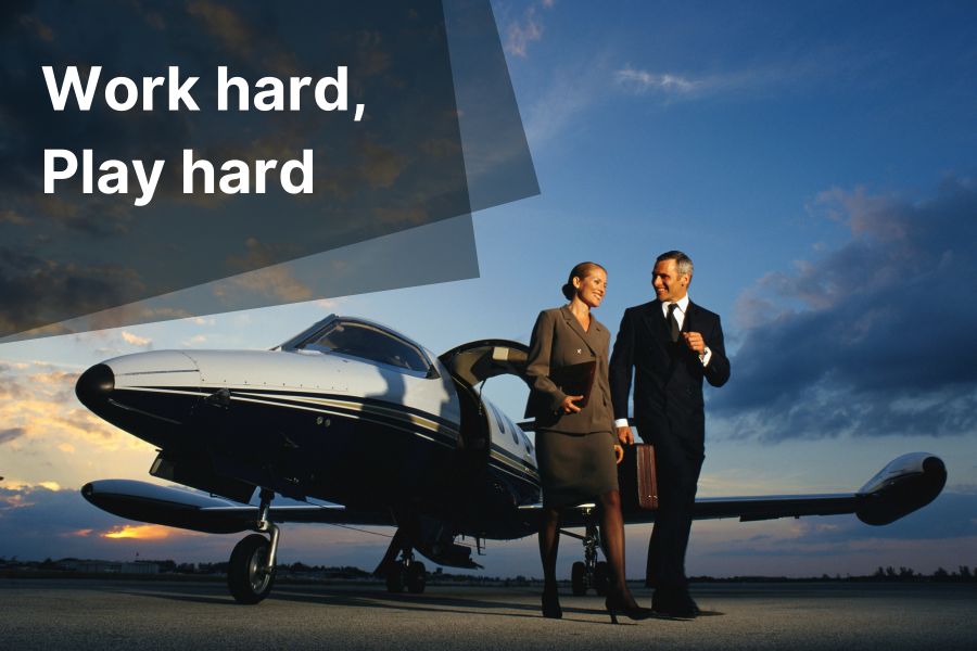 Business man and woman in front of private plane with caption Work hard Play Hard